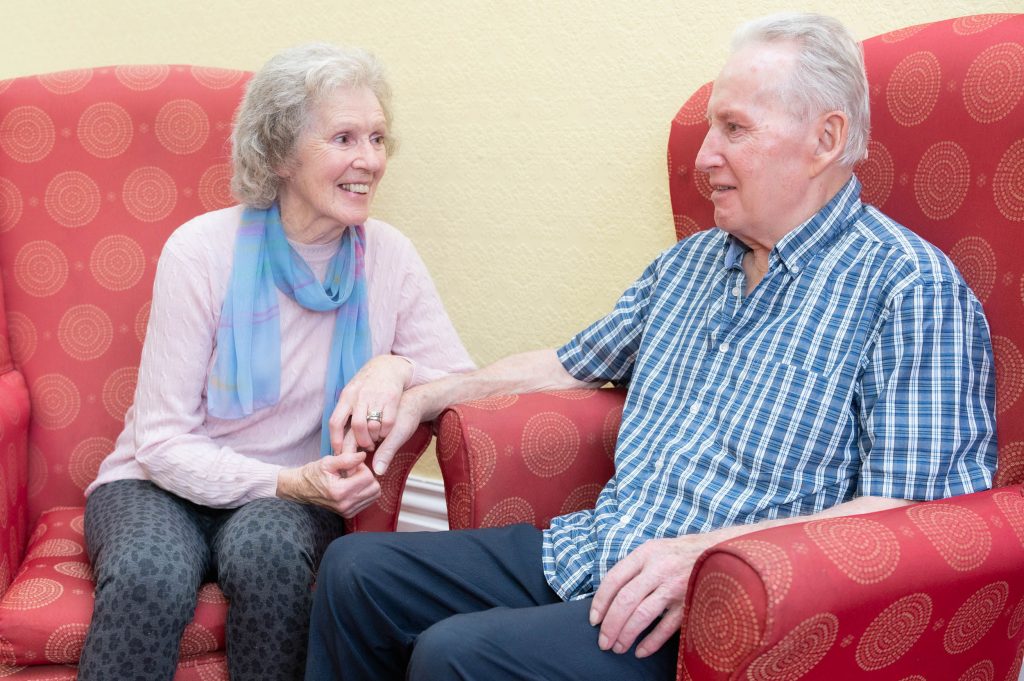 Elderly resident chatting and holding hands with elderly woman